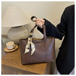 Detail der braunen Vintage-Leder-Einkaufstasche mit elegantem Seidenschal am Griff