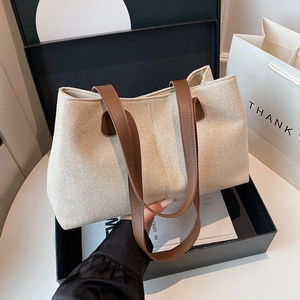 Minimalist beige canvas tote bag with brown leather handles and spacious design