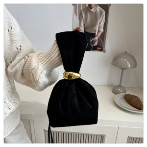 Detail of a black velvet bucket bag with an irregular gold ring in a minimalist setting