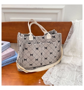 Detail of grey corduroy tote bag featuring bow patterns, quilted texture and dual pockets