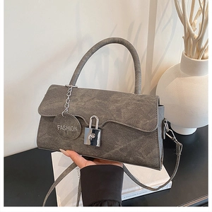 Close-up of grey textured handbag with silver padlock and decorative fashion tag