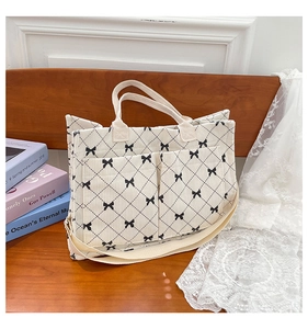 Detail of white corduroy tote bag with black bow lattice pattern and front pockets