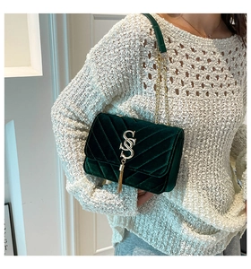 Detail of dark green velvet bag featuring V-quilted texture and gold tassel hardware