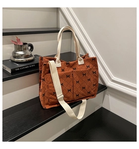 Macro detail of brown corduroy tote bag with bow patterns and adjustable strap