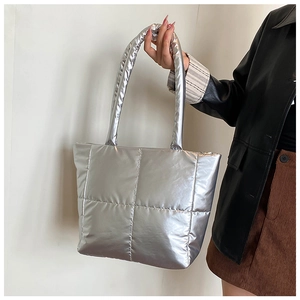 Macro shot of silver quilted puffer tote bag with metallic finish and square stitching