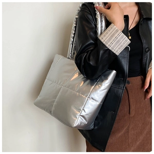 Detail of silver metallic quilted tote bag with padded handle worn by model