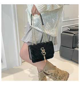 Détail du sac à chaîne en velours noir avec logo SS en métal doré et élégant pompon