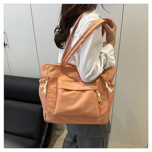 Detail view of the orange-pink nylon tote bag with functional pockets and white zip cords