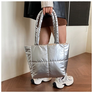Detail of silver metallic quilted tote bag featuring a padded handle and high-shine finish