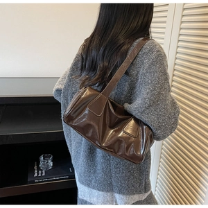 Detailed view of coffee brown patent leather shoulder bag on model with vintage aesthetic