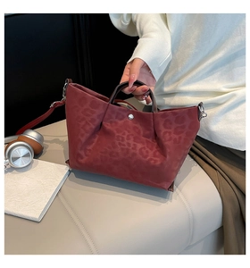 Close-up of burgundy leopard print tote bag with ruched texture and silver buckle