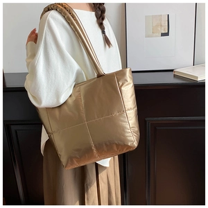 Detailed close-up of champagne gold quilted tote bag with metallic gloss finish