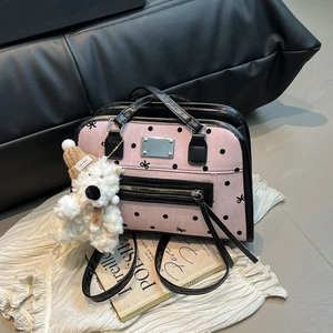 Pink polka dot tote bag with black bow print and cute plush bear charm on a magazine