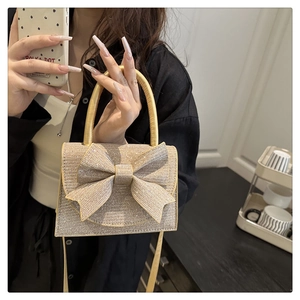 Detail of a sparkling rhinestone evening bag with a large bow and metallic finish