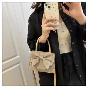 Detail of a sparkling gold evening bag with a large bow and metallic crossbody strap