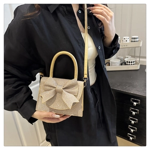 Detail of glitter champagne gold evening clutch with large bow and leather strap