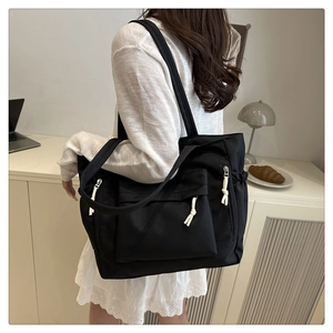 Detail of black nylon tote bag showing durable material and white rope zipper pullers