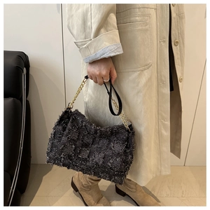 Detail of grey checkered tweed shoulder bag with tassel edges and gold chain strap