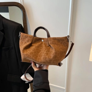 Brown leopard print tote bag with brown handles and a metal buckle shown in a lifestyle view