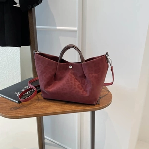 Burgundy leopard print tote bag with adjustable shoulder strap on a wooden table