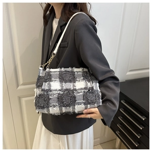 Detail of checkered tweed shoulder bag with fringe edges and gold chain link strap