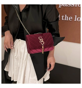 Close-up of burgundy velvet handbag with V-shaped quilting and golden tassel detail