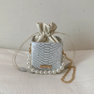 Detail of snake print mini bucket bag with pearl handle and golden chain strap