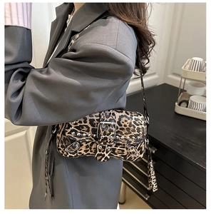 Detail of leopard print shoulder bag with silver studs and buckle strap on a model