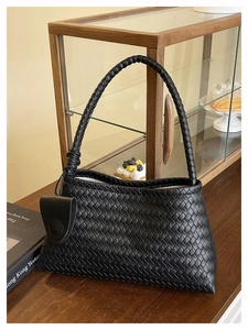 Gros plan sur la texture en cuir tressé noir et les détails de nœuds du sac à main