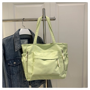 Detail view of mint green tote bag with multiple pockets and silver metallic zippers