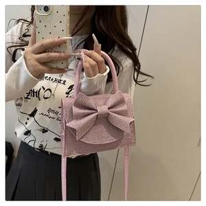 Sparkling pink glitter handbag with large bow detail shown in a mirror selfie style