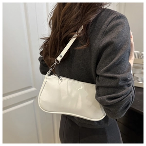 Detailed back view of a white patent leather baguette bag worn over a grey sweater