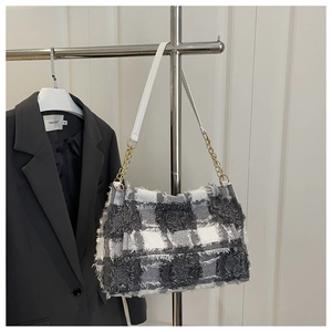 Détail d'un sac bandoulière en tweed à carreaux noir et blanc avec franges et chaîne