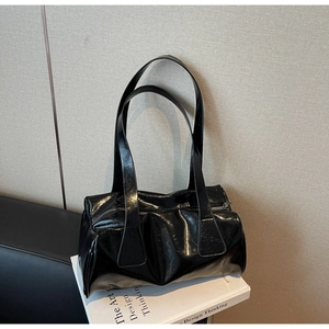 Detail shot of black glossy patent leather baguette bag with silver zipper closure