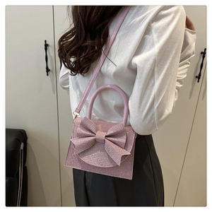 Model wearing a pink sequin handbag with a large bow detail and pearl style handle