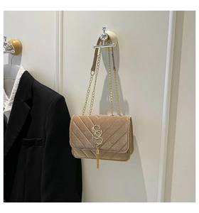 Detail of apricot quilted velvet bag with golden double S buckle and chain strap