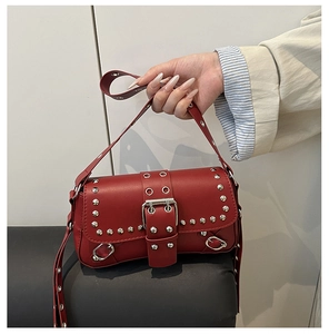Detail of red punk shoulder bag with silver studs, metal eyelets and large buckle strap