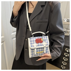 Detail of blue plaid crossbody bag with red apple print and yellow decorative strap