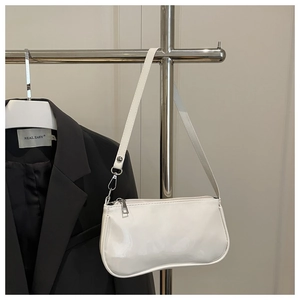 Detail of white glossy patent leather baguette bag with metal zipper and shoulder strap