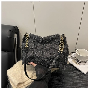 Gros plan sur un sac à bandoulière en tweed matelassé avec chaîne dorée en décor épuré