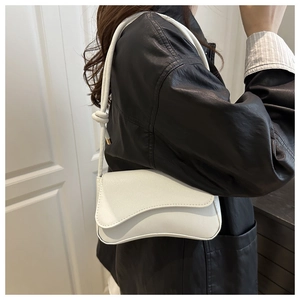 Close-up of white minimalist shoulder bag with litchi grain and knot strap detail
