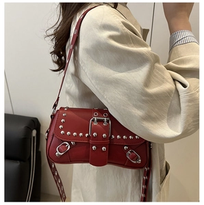 Detail of red punk leather underarm bag with silver studs and wide metal buckle strap