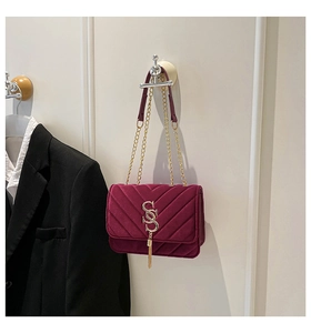 Detail of burgundy velvet quilted bag with golden S logo and tassel fringe detail