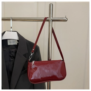 Detail of deep red patent leather shoulder bag with silver hardware and glossy finish