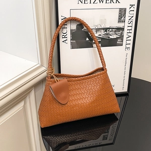 Grand sac cabas tressé marron en cuir avec poignée et breloque sur surface miroir