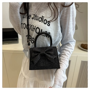 Detail view of black glitter evening bag with large bow and detachable crossbody strap