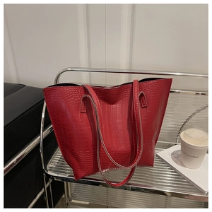 Detailed macro view of large red tote bag featuring premium crocodile embossed leather texture