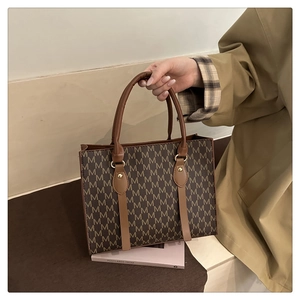 Detail of vintage brown tote bag featuring all-over monogram pattern and leather straps