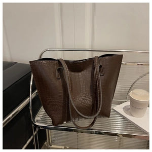 Macro detail of dark brown tote bag with premium crocodile embossed texture and leather sheen