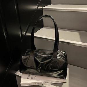 Minimalist black glossy faux leather Boston bag on modern steps with a book decor